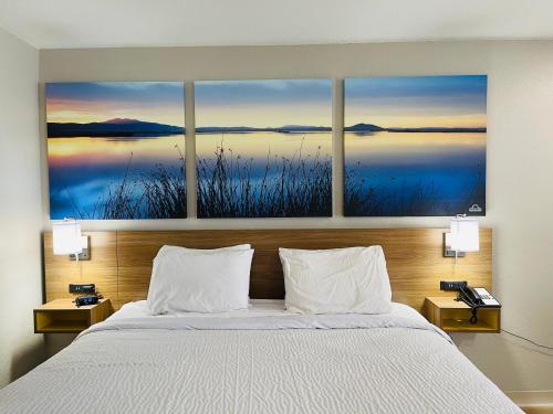基林Days Inn by Wyndham Killeen Fort Hood的卧室配有一张壁挂着四幅画作的床