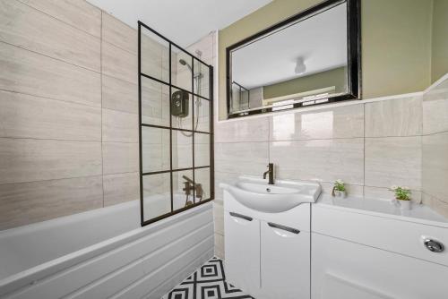 纽尼顿BridgeCity Cheerful 3 bedroom home in Nuneaton的浴室配有盥洗盆、镜子和浴缸