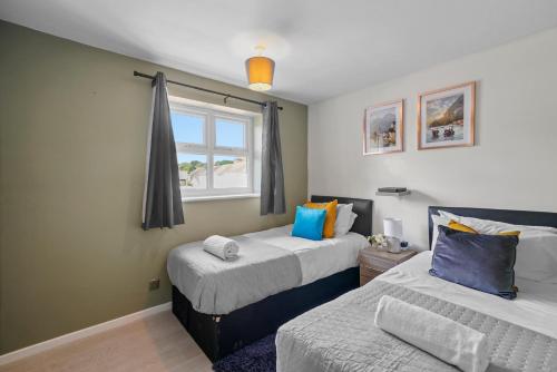 纽尼顿BridgeCity Cheerful 3 bedroom home in Nuneaton的一间卧室设有两张床和窗户。