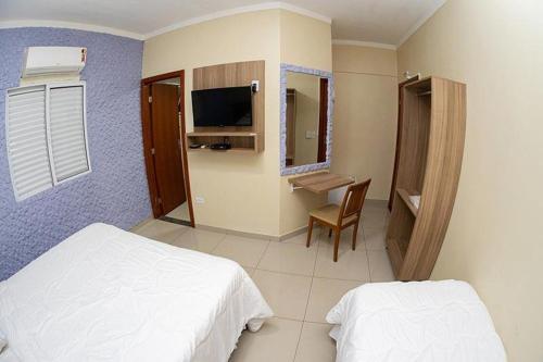 大坎普Aeroporto Plaza Hotel的一间卧室配有两张床、一张桌子和一台电视。