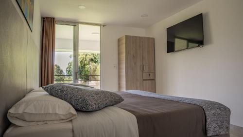 佩雷拉Hotel Palo Grande CF Pereira的卧室配有一张床铺,墙上配有电视