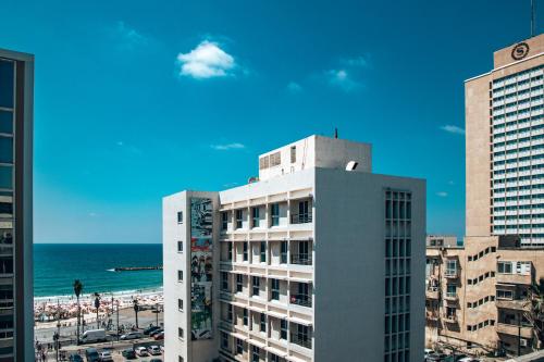 特拉维夫Selina Frishman Tel Aviv的一座高大的白色建筑,背靠海滩