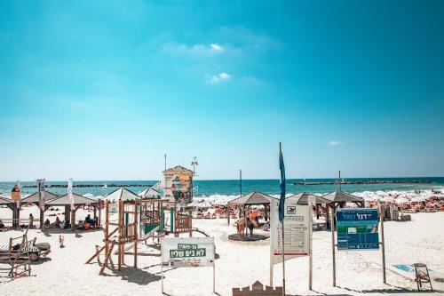 特拉维夫Selina Frishman Tel Aviv的海滩上设有椅子和遮阳伞,还有大海