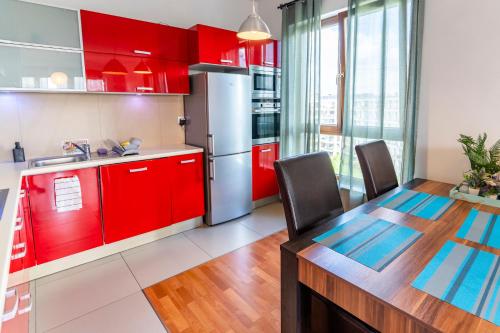 华沙FIRST -- Green Żoliborz apartment 3的厨房配有红色橱柜和桌椅