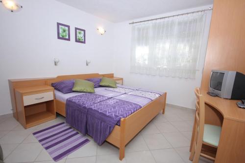 斯拉诺Apartments by the sea Slano, Dubrovnik - 8608的一间卧室配有一张床、一张书桌和一台电视。