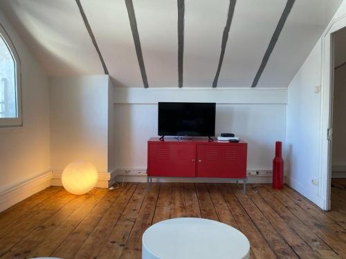 波城Chez Fabien的客厅配有红色橱柜和平面电视。