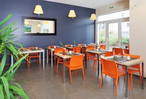 克莱蒙费朗厄斯德姆克莱蒙费朗日尔戈维亚酒店的用餐室配有桌子和橙色椅子