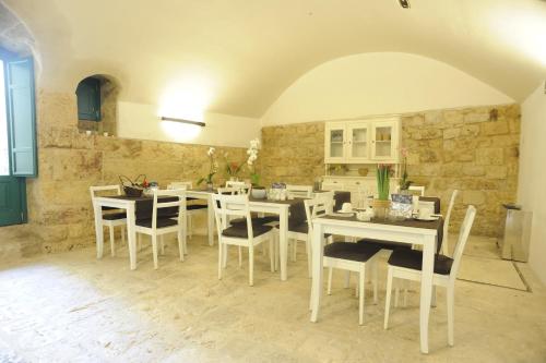 阿尔塔穆拉Il Nido dei Falchi B&B的一间设有白色桌椅和石墙的用餐室