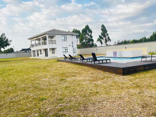 MʼBazwaneHeavenly Towers的一座房子,在院子里设有游泳池和椅子