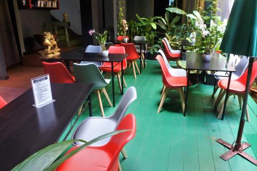 卡伦海滩Hi Karon Beach的一间设有红色椅子和桌子的餐厅,种植了植物