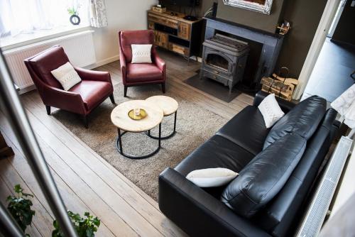 斯帕La Sentinelle Gite的客厅配有黑色真皮沙发和椅子