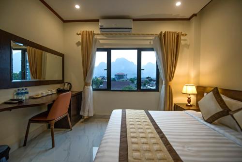 万荣Vang Vieng Freedom Star's Hotel的一间卧室配有一张床、一张书桌和一个窗户。