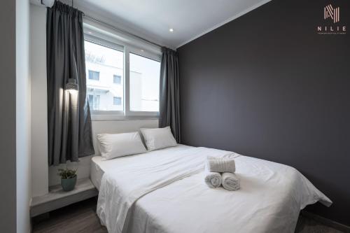 塞萨洛尼基Bourn, Nilie Hospitality MGMT的卧室配有白色的床和2条毛巾