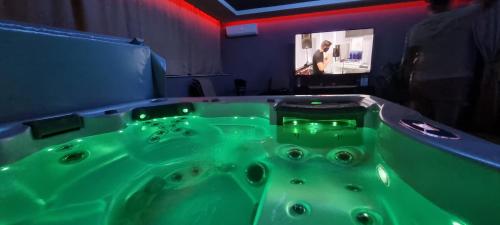 奥拉迪亚Jacuzzi Home的带电视的客房内的绿色浴缸