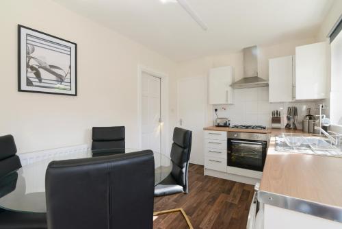 诺丁汉Alderton House - Spacious 3 Bed with Parking的厨房配有白色橱柜和桌椅