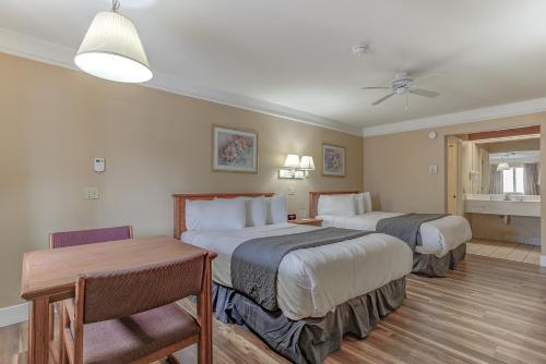 BurneyShasta Pines Motel & Suites的酒店客房设有两张床和一张桌子。
