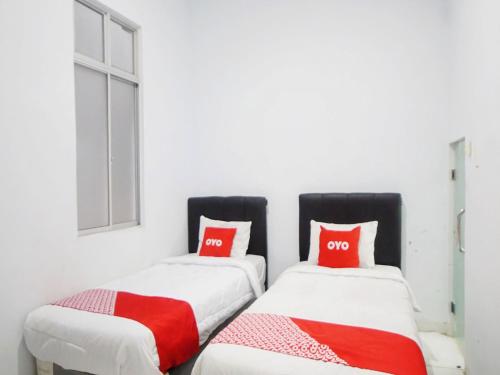 棉兰SUPER OYO 91627 Wika Wiki Homestay的宿舍间内的两张床,配有红色枕头