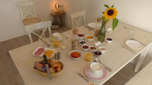 PijnackerBed en Brood Donna的一张带早餐食品的桌子和一个带向日葵的花瓶