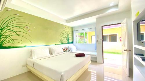 Takua Pa瓜巴度假酒店的卧室配有白色床,墙上挂有植物壁画