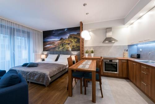 弗罗茨瓦夫EXCLUSIVE Aparthotel的一间卧室配有一张床铺和一张桌子,还设有一间厨房