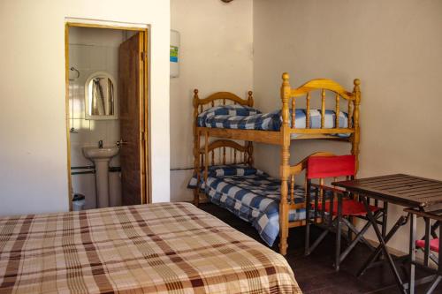 洛斯佩妮滕特斯Altas Cumbres Penitentes的一间卧室配有一张床、一张桌子和一张双层床。