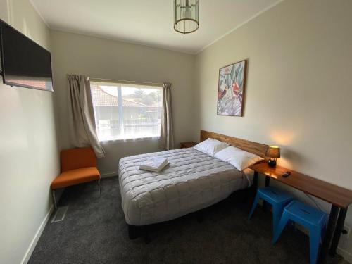 奥克兰Airport Westney Lodge的一间卧室配有一张床、一张书桌和一个窗户。