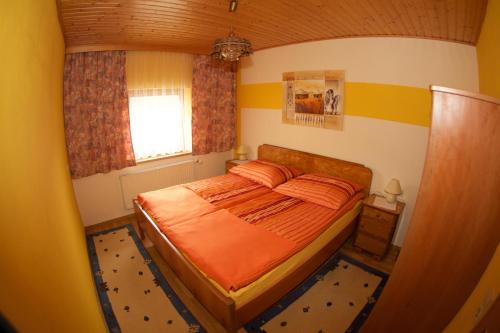 ReisachHaus Stöffler的一间卧室配有带橙色床单的床和窗户。