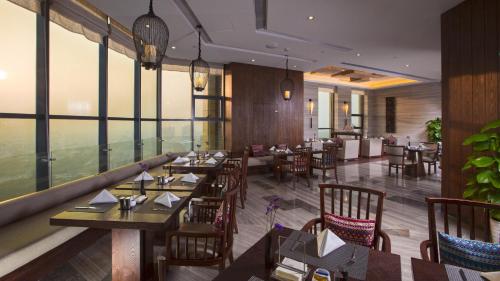 德清莫干山德蓝君亭酒店的餐厅设有木桌、椅子和窗户。