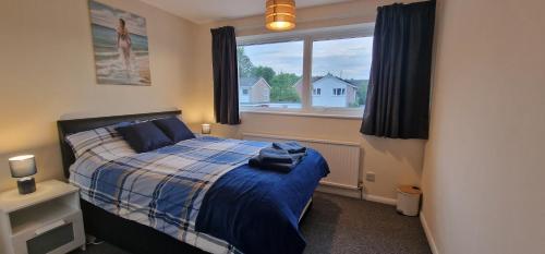 MiltonShirley L, Milton, Cambridge, 4 BR House, Newly Refurbished的一间卧室配有一张带蓝色毯子的床和窗户。