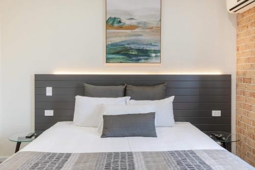 布里斯班库珀殖民式汽车旅馆的卧室配有白色床和灰色床头板