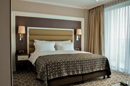 阿菲永ALUSSO THERMAL HOTEL SPA的一间卧室设有一张大床和一个大窗户