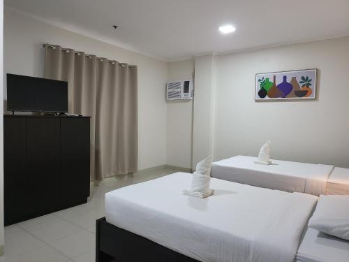马尼拉Rooms R Us - Evangelista的酒店客房设有两张床和电视。