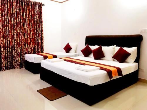马希延格讷New Rest House Inn的一间卧室配有两张带红色枕头的床