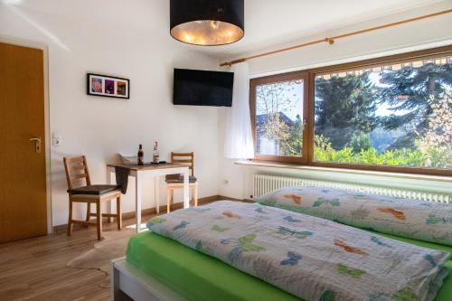 Friedenweilerstuub simonswinkel的一间卧室配有一张床、一张桌子和一个窗户。