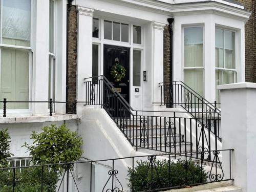 伦敦Stylish 3-bedroom flat in Kensington的白色的房子,有黑色的门和楼梯