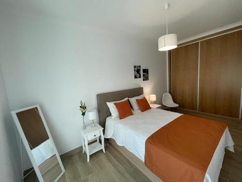 蒙希克Alojamento S. Gabriel 1的一间卧室配有带橙色枕头和镜子的床