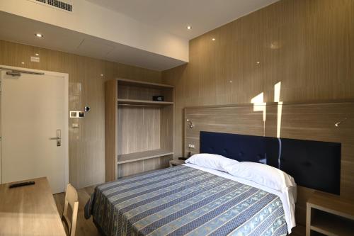 米兰Hotel Midway的一间卧室配有一张带蓝白色毯子的床