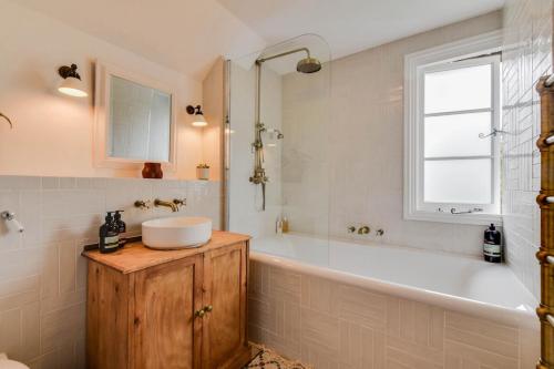 赛伦塞斯特Cheerful 3 bed Grade II Central Cottage的带浴缸、水槽和窗户的浴室