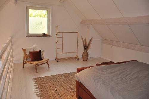 NieuwlandB&B Sonnehuys的一间卧室设有一张床、一个窗口和一把椅子