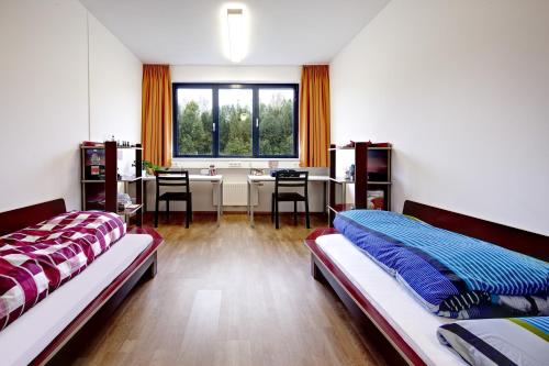 萨菲登安斯泰内嫩米尔Alm 34 mit 24 Stunden Self Check in的一间卧室设有两张床、一张桌子和一个窗口。