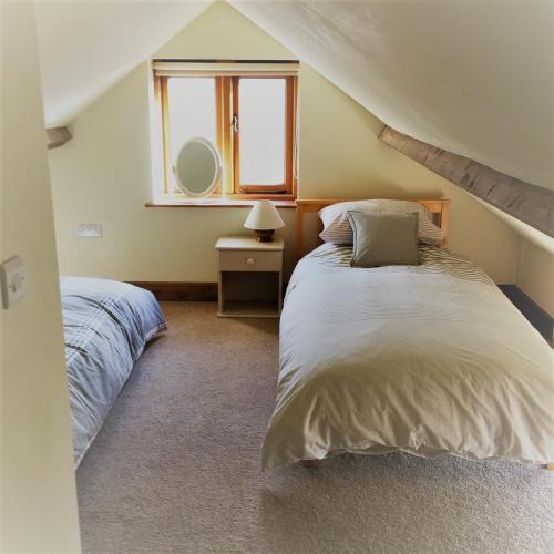 汤顿Meg's Cottage的一间卧室设有两张床和窗户。