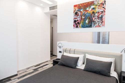 维博瓦伦蒂亚Palazzo IrMa - Hotel - B&B Luxury的卧室配有一张床,墙上挂有绘画作品