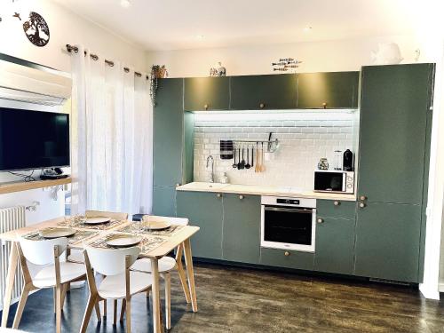 卢贝新城Baie-Des-Anges Studio Front de Mer的厨房配有绿色橱柜和一张带白色椅子的桌子