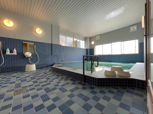 别府Guesthouse Sunline Beppu的一间大浴室,内设一个蓝色瓷砖游泳池