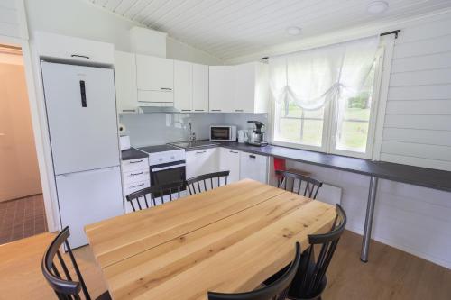 卡亚尼Lomaperkkiö Cottages的厨房配有木桌和椅子