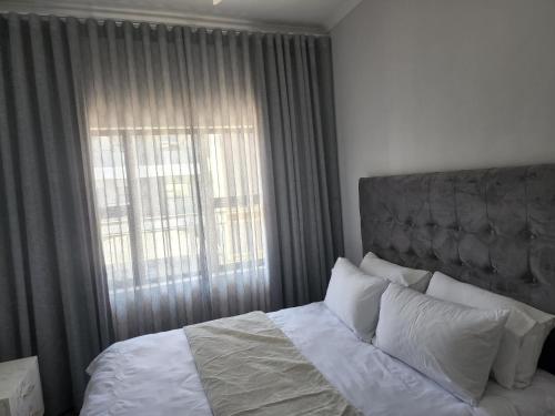 哈博罗内Sarona city Habitat Alpha apartments C202 Gaborone的一间卧室设有一张大床和大窗户