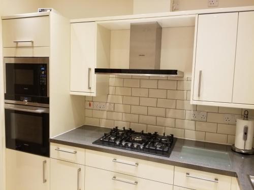 WansteadLondon Luxury Apartments 1 min from Redbridge Station with Parking的厨房配有白色橱柜和炉灶烤箱。