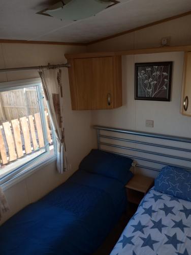 阿贝尔格莱B58 is a 3 bedroom 8 berth caravan close to the beach on Whitehouse Leisure Park Towyn near Rhyl with private parking space This is a pet free caravan的一间小卧室,配有两张床和窗户