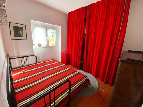 里斯本Casa das Boganvilias - Moradia com jardim的一间卧室配有红色窗帘、一张床和窗户