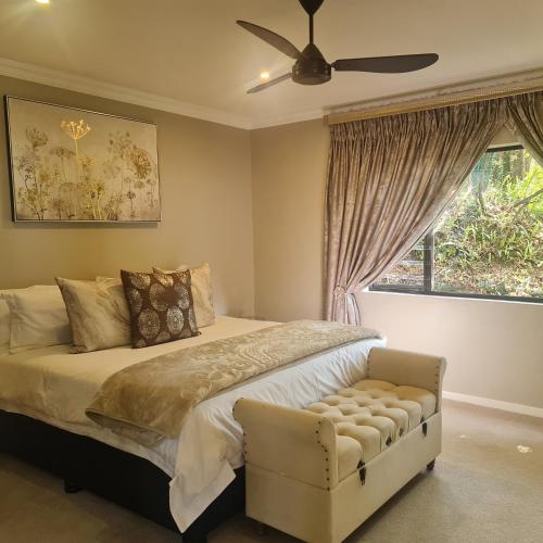 BergviewLuxury Home with breathtaking views of Champagne Valley的一间卧室配有一张带吊扇和窗户的床。